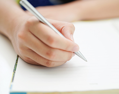 a person holding a pen writing on a notepad