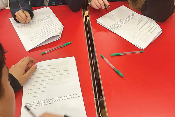 three GCSE students going through a practice exam paper on a red table